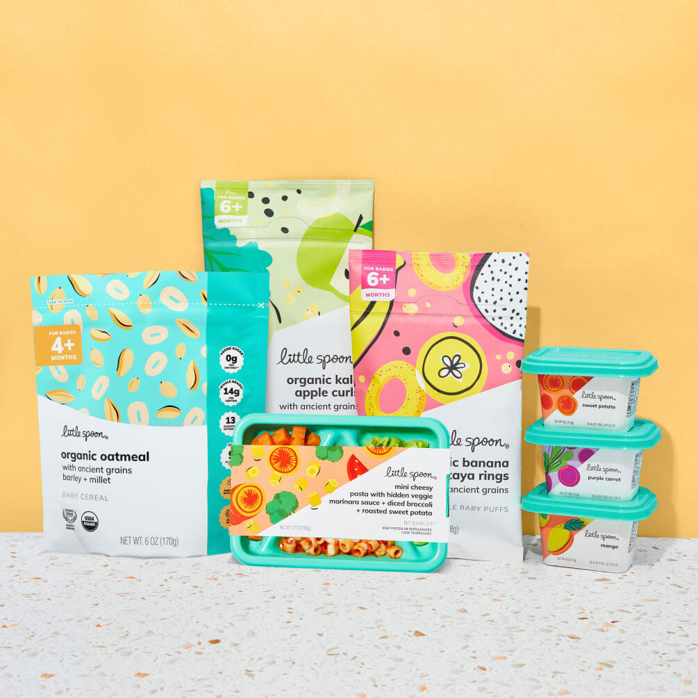Little Spoon product lineup, including organic oatmeal baby cereal, kale apple curls, banana papaya rings, a Biteables tray, and assorted Babyblends containers, arranged against a yellow background.